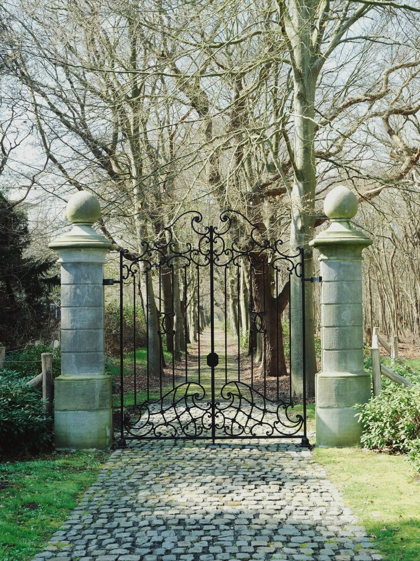 Cantilever sliding gate at ornamental park entrance on cobblestone