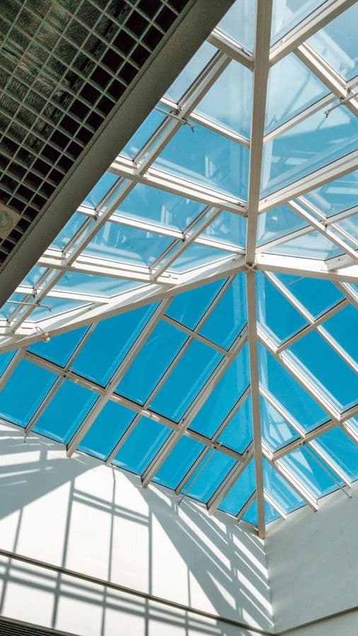 Modern glass skylight ceiling looking up at blue sky